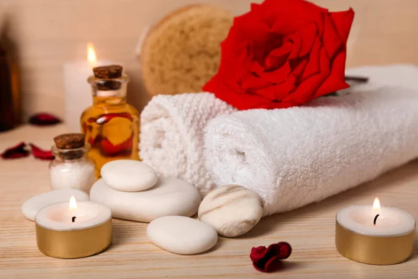 Spa stones with towels, rose and candles on wooden table, closeup. Valentine\'s Day celebration