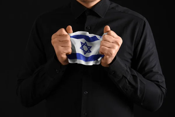 Jewish man with flag of Israel honoring victims of Holocaust on dark background