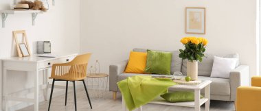 Odanın içindeki masanın üzerinde güzel sarı güller olan vazo.