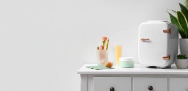 Odadaki ışık duvarının yanındaki masada küçük bir kozmetik buzdolabı.