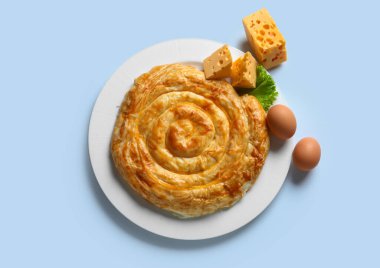 Lezzetli peynirli turta ve mavi arka planda malzemeler.