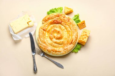 Lezzetli peynirli turta ve bej arka planda malzemeler.