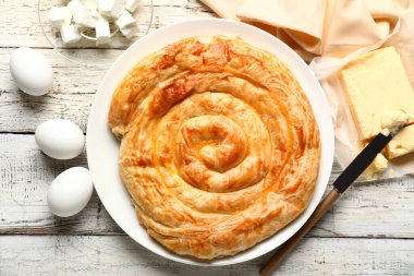 Lezzetli peynirli turta ve beyaz ahşap masa malzemeleri.