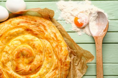 Lezzetli peynirli turta ve yeşil ahşap masadaki malzemeler