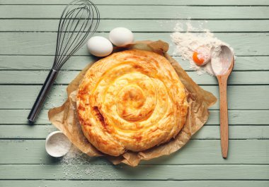 Lezzetli peynirli turta ve yeşil ahşap masadaki malzemeler