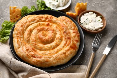 Lezzetli peynirli turta, marul ve malzemeler gri masada.