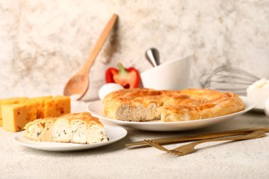 Lezzetli peynirli turta ve beyaz masadaki malzemelerle dolu bir tabak.