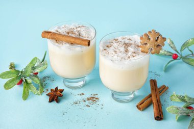 Renkli arkaplanda lezzetli eggnog kokteylleri, baharatlar ve ökseotu.