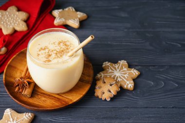 Bir bardak nefis eggnog kokteyli ve koyu ahşap arka planda Noel kurabiyesi.