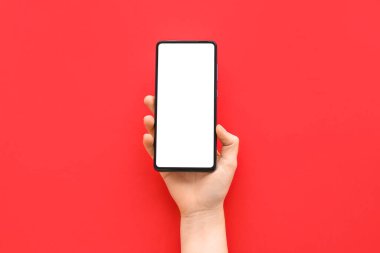 Female hand with modern mobile phone on red background