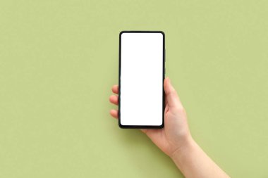 Female hand with modern mobile phone on green background