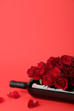 Roses with bottle of wine on red background. Valentine's Day celebration