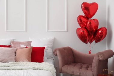 Armchair with balloons for Valentine's Day in interior of light bedroom