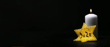 David star and burning candle on dark background with space for text. International Holocaust Remembrance Day