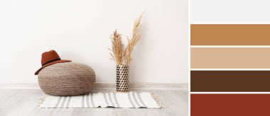 Stylish pouf with hat, vase with floral decor and rug near white wall in room. Different color patterns