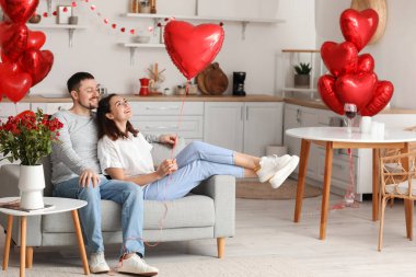 Happy couple sitting in kitchen on Valentine's Day