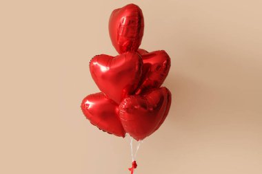 Bej duvarın yanında Sevgililer Günü için kalp şeklinde balonlar.
