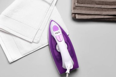 Açık gri arkaplanda elektrikli demir ve pamuk havlular