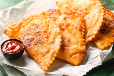 Lezzetli chebureks ve soslu parşömen, yakın plan.