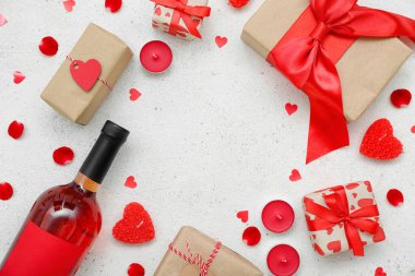 Hediyeler, mumlar, şarap şişesi ve beyaz arka planda kalplerden yapılmış çerçeveler. Sevgililer Günü kutlaması