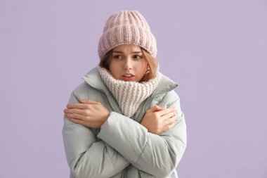 Leylak arka planında kışlık giysiler içinde donmuş genç bir kadın.