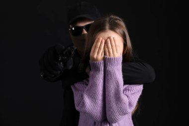 Silahlı terörist ve siyah arka planda küçük bir rehine.