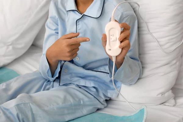 Little boy pointing at electric heating pad in bedroom, closeup