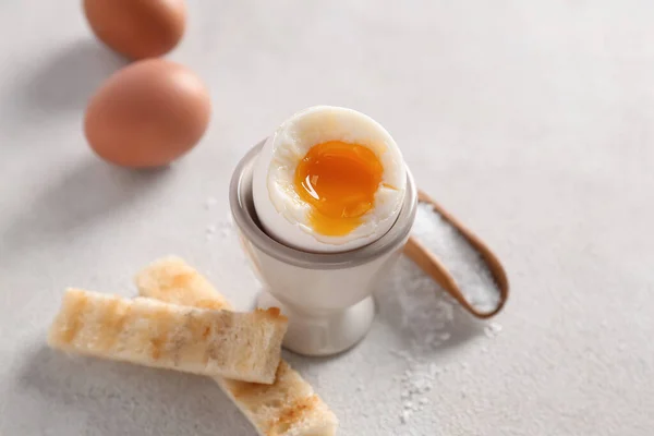 Holder with soft boiled egg and toasted bread on white table