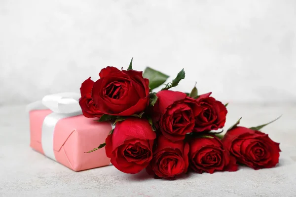 Red roses and gift on light background. Valentine\'s Day celebration