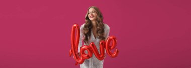 Balon şeklinde balonu olan güzel bir genç kadın. Renkli arka planda aşk var. Sevgililer Günü kutlaması