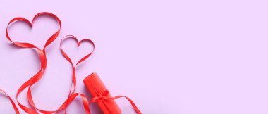 Hearts made of red ribbon and gift on lilac background with space for text. Valentine's Day celebration