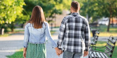 Happy couple walking in park on spring day, back view