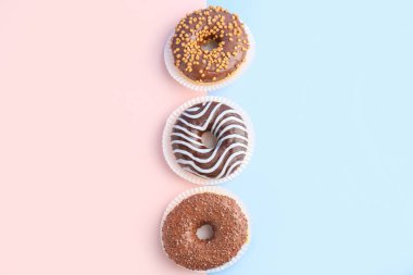 Delicious chocolate donuts on color background