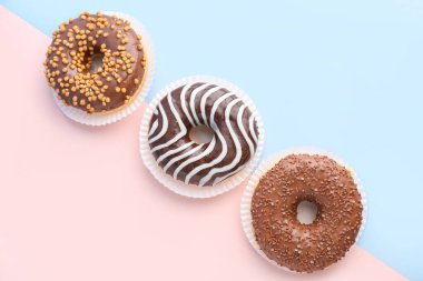 Delicious chocolate donuts on color background