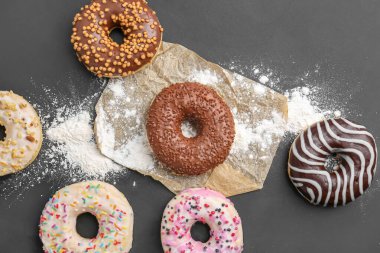 Delicious donuts and sugar powder on dark background