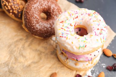Sheet of baking paper with tasty donuts, closeup