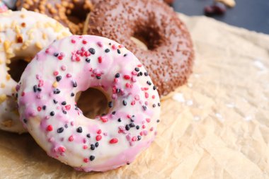 Sheet of baking paper with tasty donuts, closeup