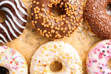 Sheet of baking paper with tasty donuts, closeup