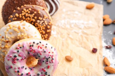 Sheet of baking paper with tasty donuts, closeup