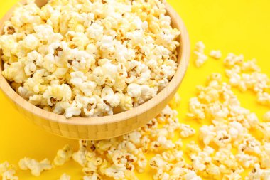 Bowl of tasty popcorn on yellow background, closeup