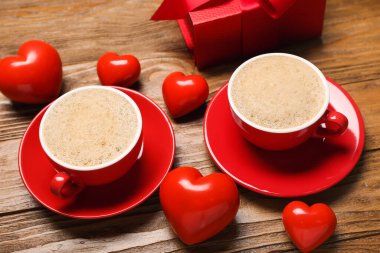 Bir fincan latte, kalpler ve hediye ahşap arka planda, yakın plan. Sevgililer Günü kutlaması