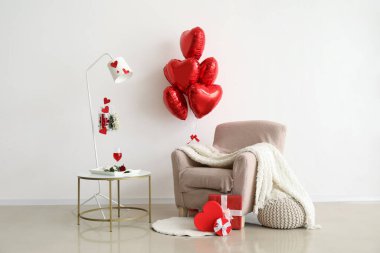 interior of light living room decorated for Valentine's Day with balloons, armchair and table