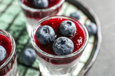 Plate with shots of delicious chia seed pudding and blueberry on black table, closeup
