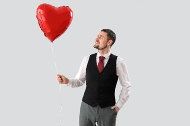 Işık arka planında kalp şeklinde balonu olan yakışıklı bir adam. Sevgililer Günü kutlaması