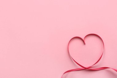 Heart made of ribbon on pink background. Valentine's Day celebration