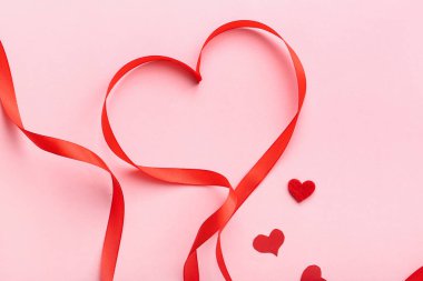 Red ribbon with hearts on pink background. Valentine's Day celebration