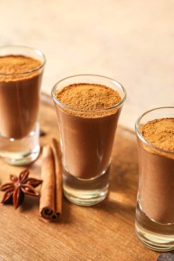 Shots of chocolate pudding with cinnamon and anise on wooden board, closeup