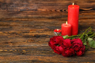 Kırmızı güller ve yanan mumlar ahşap arka planda. Sevgililer Günü kutlaması
