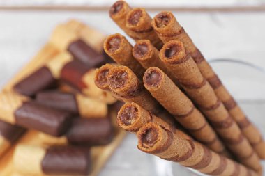 Delicious rolled wafer cookies on table, closeup