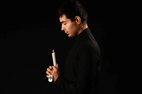 Praying Jewish man with candle on dark background. International Holocaust Remembrance Day